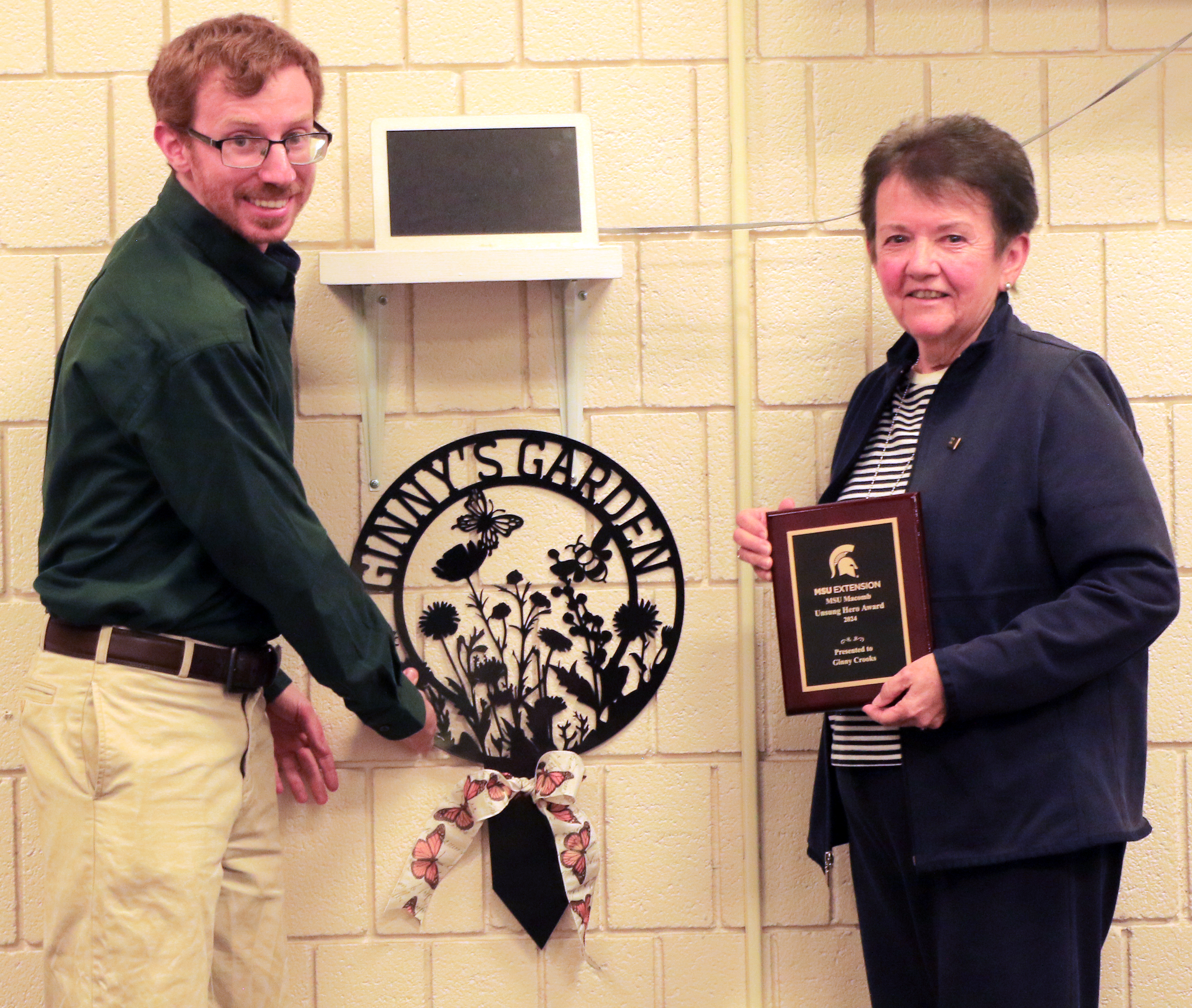 David and Ginny pose next to a metal sign that says Ginny's Garden.